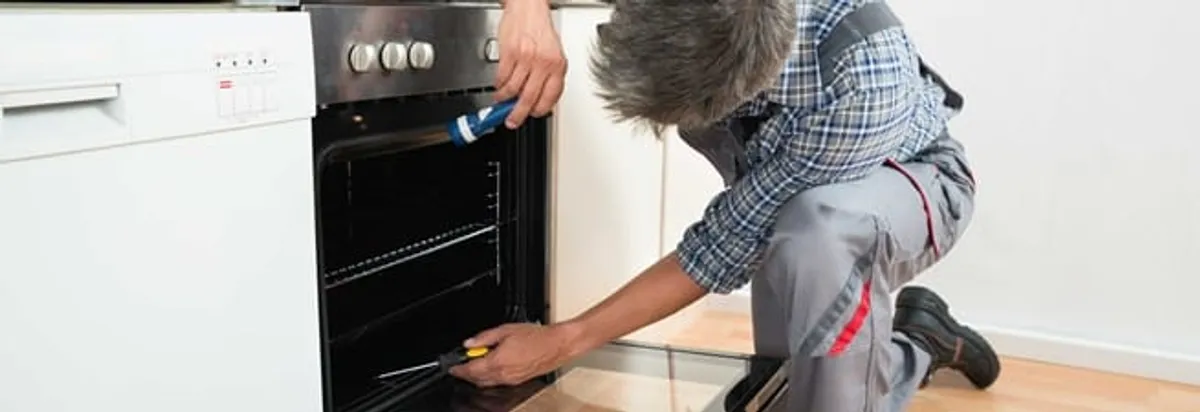 Oven repair technician inspecting and servicing an electric oven in Omaha, NE