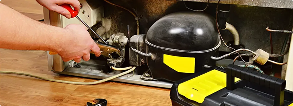 Refrigerator repair technician fixing the compressor and wiring in Omaha, NE